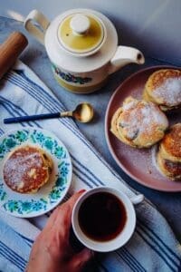 white ceramic mug with saucer beside bread on brown ceramic plate